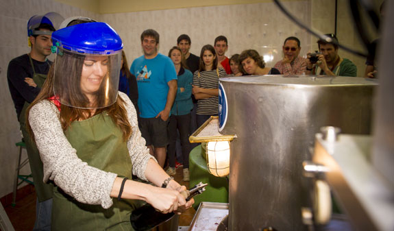 Noia desgorjant una ampolla de cava a un celler